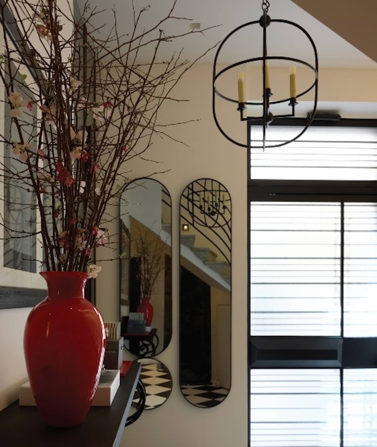 Στην αισθητική Bauhaus παραπέμπει η νέα σιδερένια πόρτα στην είσοδο του σπιτιού. Το ασπρόμαυρο μαρμάρινο δάπεδο σκακιέρα και το φωτιστικό αντικατοπτρίζονται στους οβάλ
καθρέφτες. Η κονσόλα είναι παλιά αιγυπτιώτικη, οικογενειακό κειμήλιο.